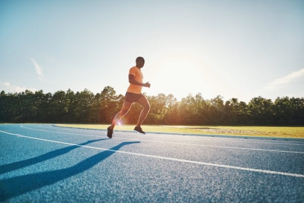 Lone athlete running along a track on a sunny day